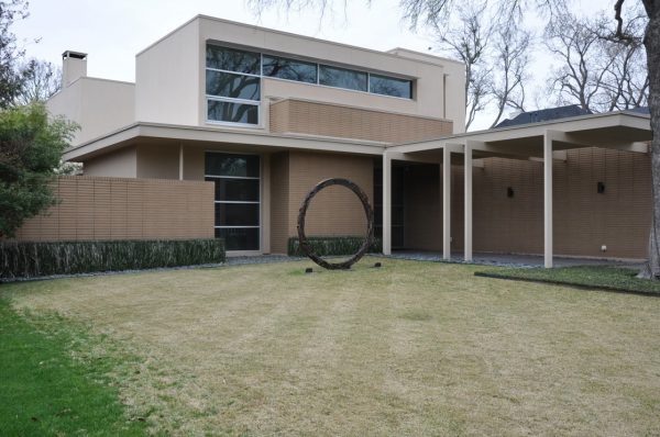 façade of a modern house with a round sculpture sited in the front yard, Informational post.
