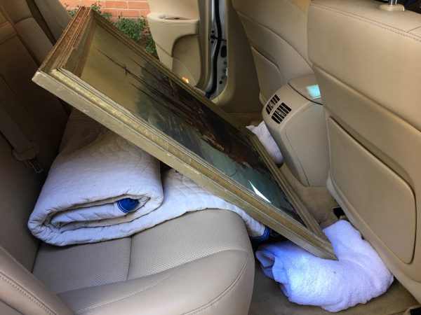 This image shows how to cushion an artwork to ride in the back of an four door sedan. Pillows on each side will keep it from falling left or right.