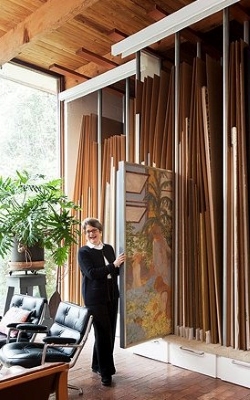 Image of Cheryl Vogel providing scale to the room by sliding a painting out of the rack.